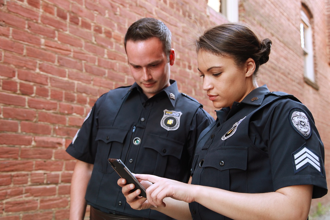Two police looking at a smartphone or PDA device