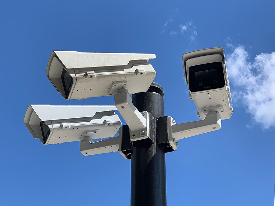 Three outdoor cameras mounted on pole in stadium